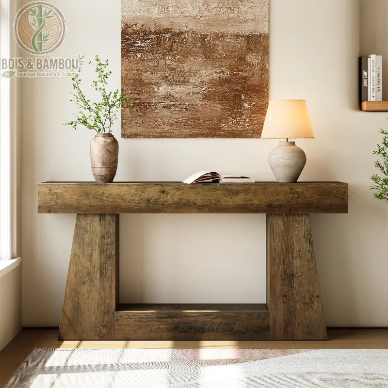 Console allongee style farmhouse 160 cm situation 4. Console robuste en bois massif au fini rustique, décorée d'une lampe et d'un vase devant un tableau abstrait, créant une ambiance sereine.
