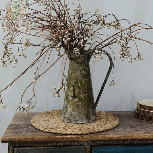 Dessous de Plat en Rotin Tressé utilisé comme napperon décoratif sur table en bois sombre avec vase et fleurs séchées