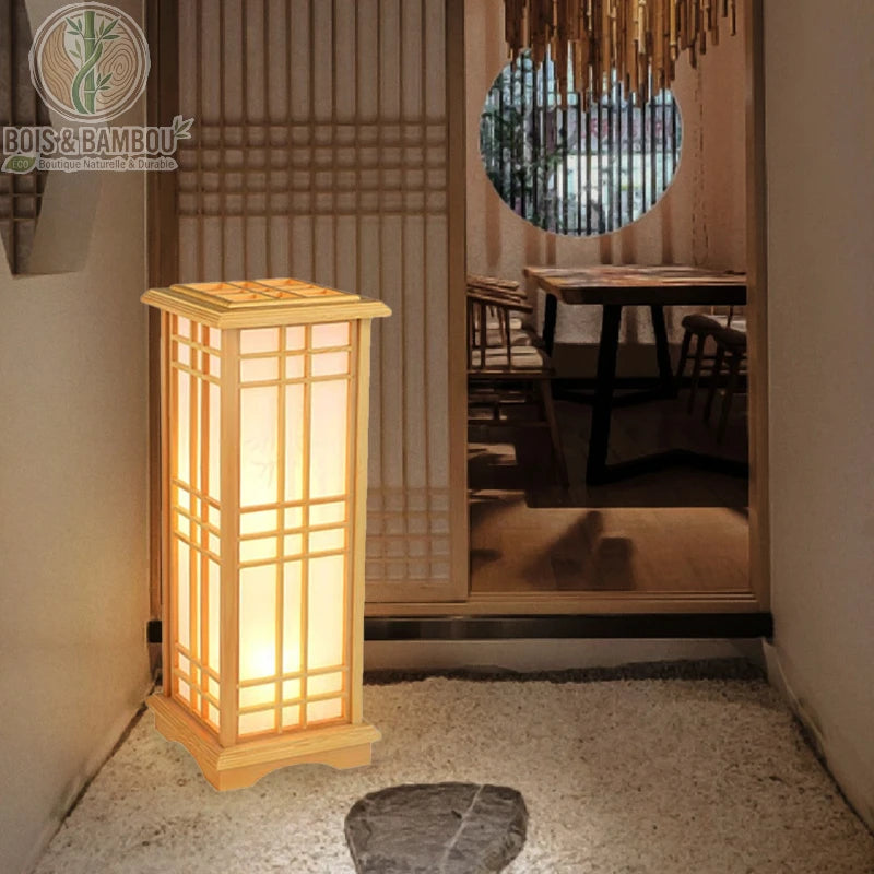 Lampadaire en bois de pin , une lanterne de sol de style japonais en bois de pin clair et papier washi, diffusant une lueur douce à l'entrée d'une pièce d'inspiration zen.