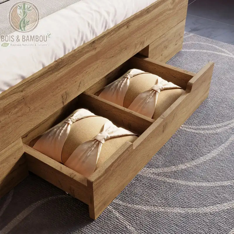 Lit Moderne en Bois Massif epure tiroire. Gros plan d'un grand tiroir de lit en bois massif ouvert, contenant des coussins beiges, intégré dans un cadre de lit au design épuré.