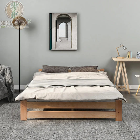 Lit Tatami en Bois de Pin 2. Un lit bas minimaliste en bois clair avec couette blanche, disposé sur un tapis gris dans une chambre moderne avec un bureau et un cadre mural d'arcade.