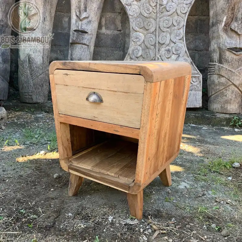 Table de chevet arrondie en bois recyclé à un tiroir et niche présentée en extérieur