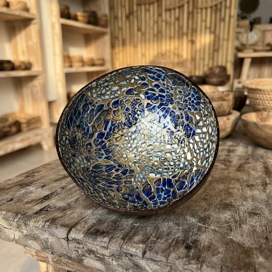 Bol en noix de coco décoratif à mosaïque craquelée bleu et or, sur une table en bois dans une boutique en bambou
