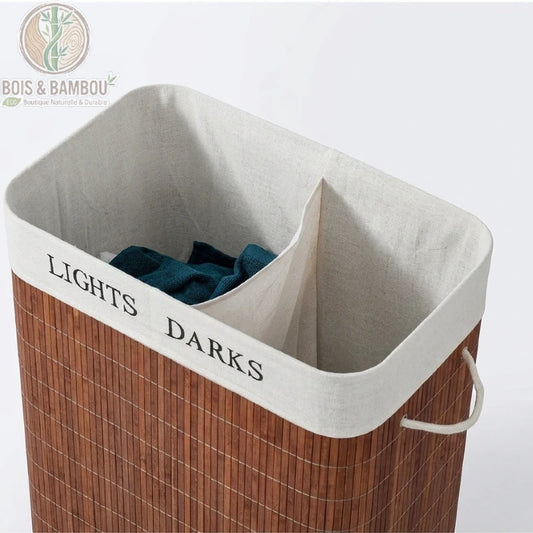 Gros plan sur l'intérieur du panier à linge en bambou 100L : doublure en tissu avec les compartiments « Lights » et « Darks » imprimés, séparateur central, linge posé à l'intérieur.
