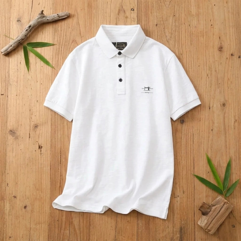 Polo homme blanc en coton et fibre de bambou posé à plat sur une table en bois brut avec feuilles de bambou