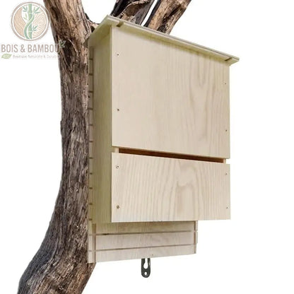 Abri pour Chauve-Souris en Bois Naturel. Un nichoir rectangulaire en bois clair conçu pour les chauves-souris, fixé verticalement sur le tronc d'un arbre avec une fente d'entrée.