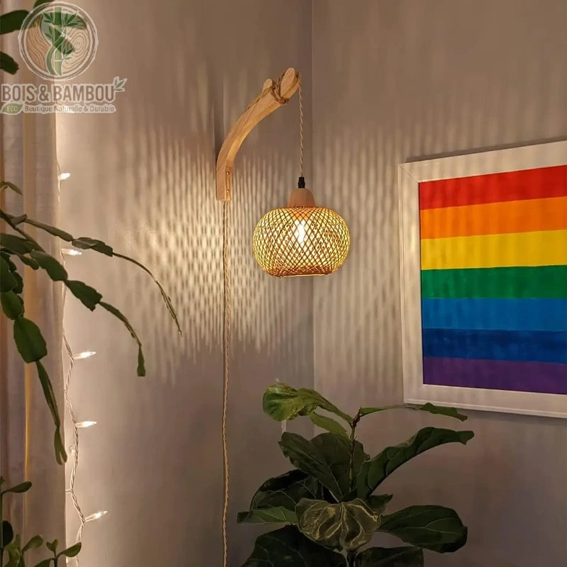 Applique lanterne bambou tressé bras bois courbé dans salon avec plantes
