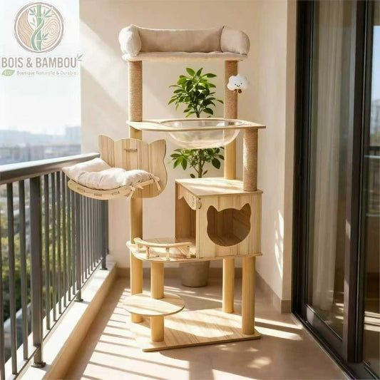 Arbre à Chat en Bois Naturel. Un grand arbre à chat multi-niveaux en bois clair installé sur un balcon, comprenant une niche, un hamac, une capsule transparente et des plateformes.
