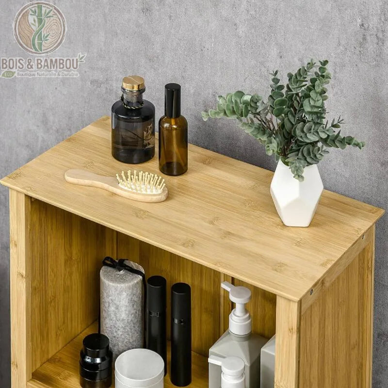 Armoire de salle de bain en bambou situation 2. Vue de dessus d'un meuble en bois clair garni de flacons cosmétiques, d'une brosse à cheveux et d'un petit vase d'eucalyptus sur fond gris béton.