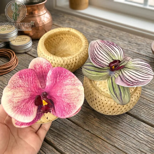 Boîte à Bijoux Orchidée en bambou tressé, avec des couvercles ornés de fleurs d'orchidées colorées sur une table en bois rustique.