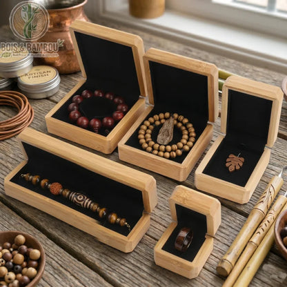 Boîte à Bijoux en Bois de Bambou ouverte révélant divers bijoux artisanaux sur velours noir, disposée sur un plan de travail en bois rustique.
