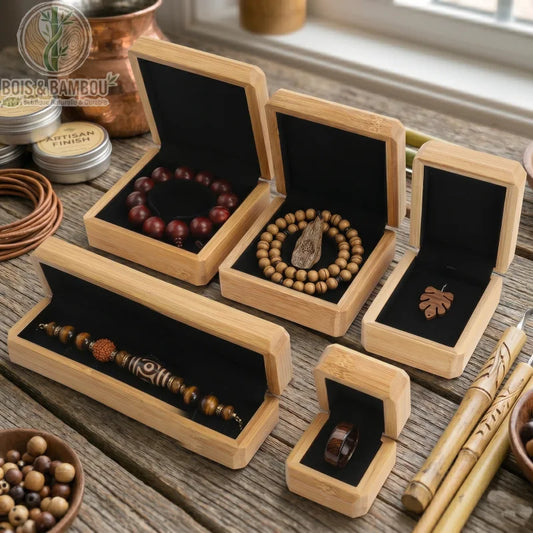 Boîte à Bijoux en Bois de Bambou ouverte révélant divers bijoux artisanaux sur velours noir, disposée sur un plan de travail en bois rustique.
