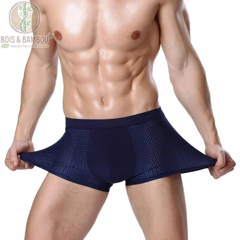 Boxer en fibre de bambou avec maille respirante. Un homme porte un boxer bleu marine extensible avec des empiècements latéraux en maille aérée, illustrant la souplesse du tissu.