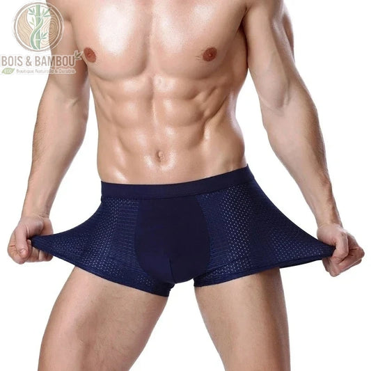 Boxer en fibre de bambou avec maille respirante. Un homme porte un boxer bleu marine extensible avec des empiècements latéraux en maille aérée, illustrant la souplesse du tissu.