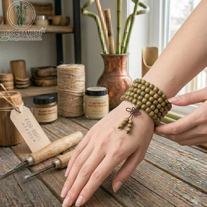 Bracelet Mala en santal vert naturel enroulé au poignet d'une artisane sur un établi de sculpture sur bois.