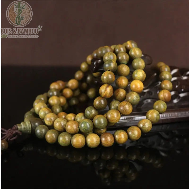 Mala santal vert naturel 108 perles Verawood couleur verte posé sur support bois sculpté fond brun