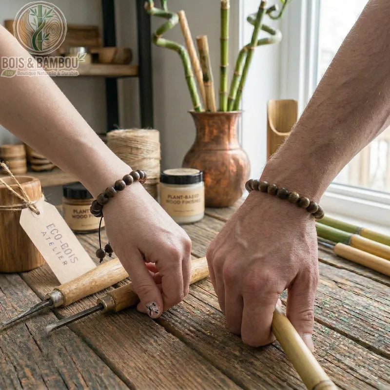 Bracelet en perles de palissandre noir porté en duo par deux artisans travaillant sur un établi en bois avec des ciseaux.