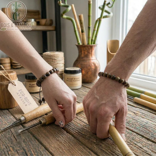 Bracelet en perles de palissandre noir porté en duo par deux artisans travaillant sur un établi en bois avec des ciseaux.