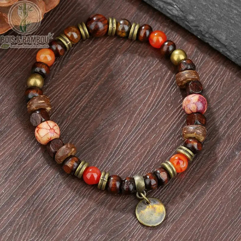 Bracelet ethnique Bodhi et œil de tigre modèle 4 perles orange rouge breloque bronze sur surface bois foncé