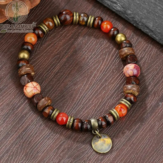 Bracelet ethnique Bodhi et œil de tigre modèle 4 perles orange rouge breloque bronze sur surface bois foncé
