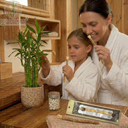 Brosse à dents Miswak rétro naturelle tenue par une mère et sa fille. Racine de siwak traditionnelle en sachet vintage sur un meuble en bois. Hygiène dentaire bio et zéro déchet.