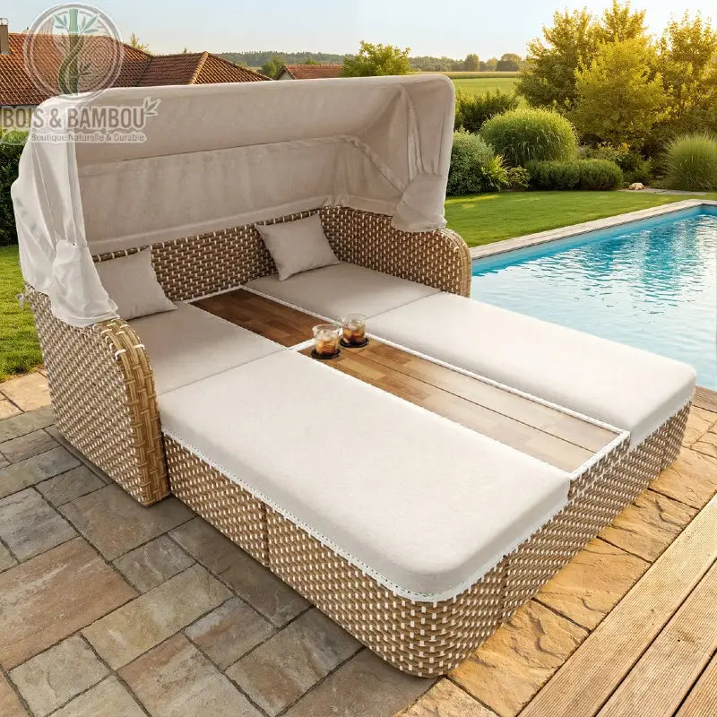 Chaise Longue en bois avec Auvent cote. Lit de jardin double en résine tressée avec coussins blancs, auvent rétractable et tablette centrale en bois, installé au bord d'une piscine ensoleillée.
