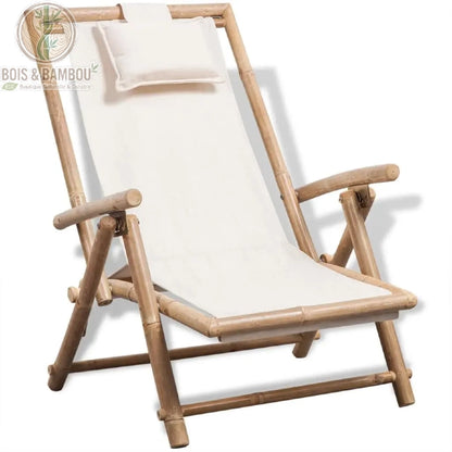 Chilienne en Bambou. Un transat pliant avec une structure en tiges de bambou naturel et une toile blanche tendue munie d'un repose-tête assorti, présenté sur un fond blanc.