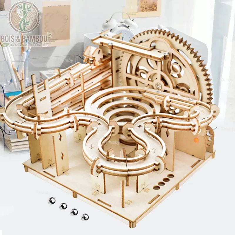 Circuit à billes Marble Run en bois. Une structure complexe de parcours à billes avec engrenages et rails sinueux, assemblée en bois découpé, accompagnée de billes métalliques.