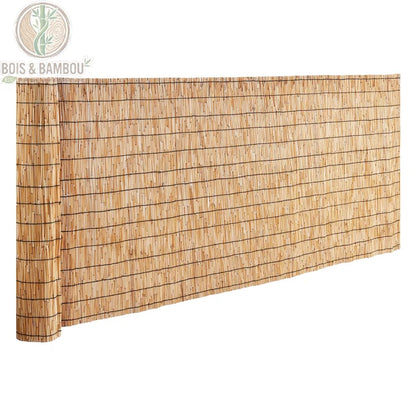 Clôture en Roseau Naturel. Un rouleau de canisse en roseaux naturels liés par des fils horizontaux, partiellement déroulé pour former un écran de protection, présenté sur fond blanc.