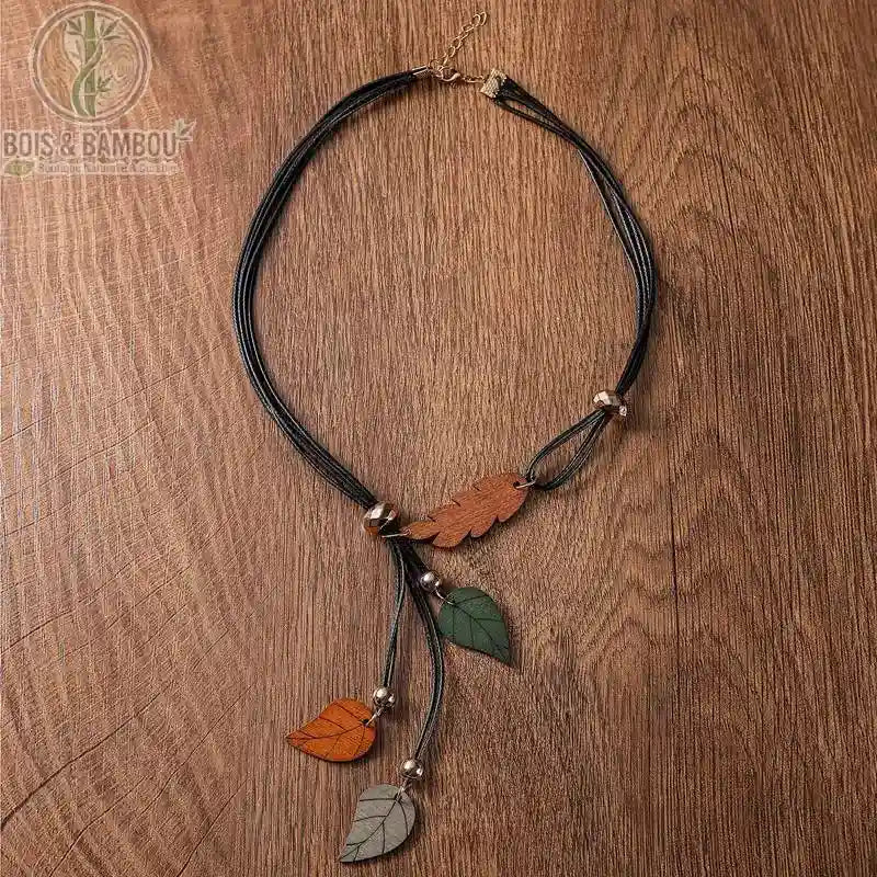 collier pendentif feuilles en bois coloris brun orange et gris vert trois feuilles sur cordon noir fond bois