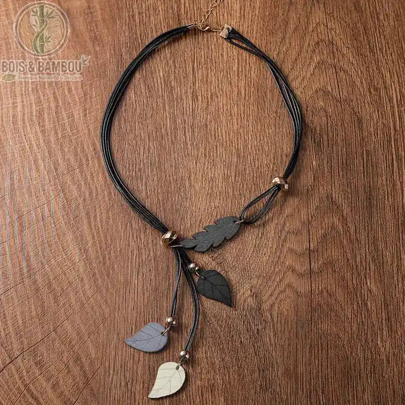 collier pendentif feuilles en bois coloris noir gris et blanc feuilles sculptées cordon multibrin fond bois