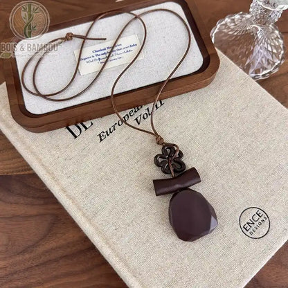 collier long bois sculpté modèle 1 pendentif goutte aplatie brun-bordeaux nœud décoratif fleur cordon brun
