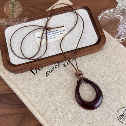 collier long bois sculpté modèle 3 pendentif anneau ovale ajouré brun-bordeaux cordon brun réglable
