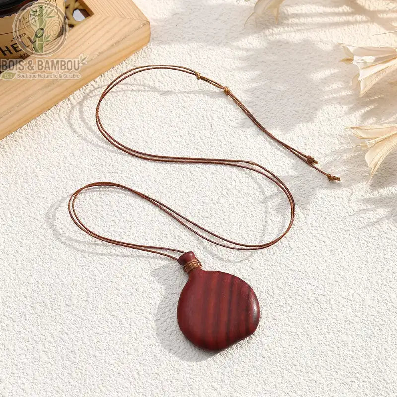Collier pendentif bois sculpté galet plat rouge strié cordon brun ajustable