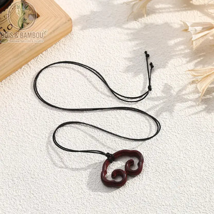 Collier pendentif bois sculpté forme nuage spirale bordeaux cordon noir