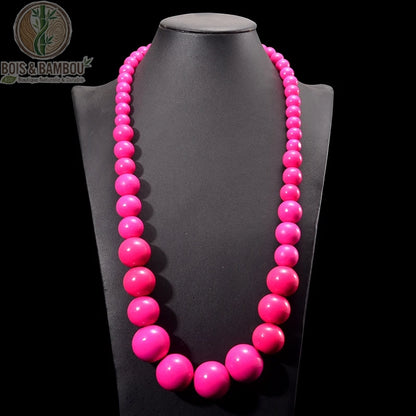 collier plastron grosses perles bois rondes coloris rose fuchsia sur buste fond sombre