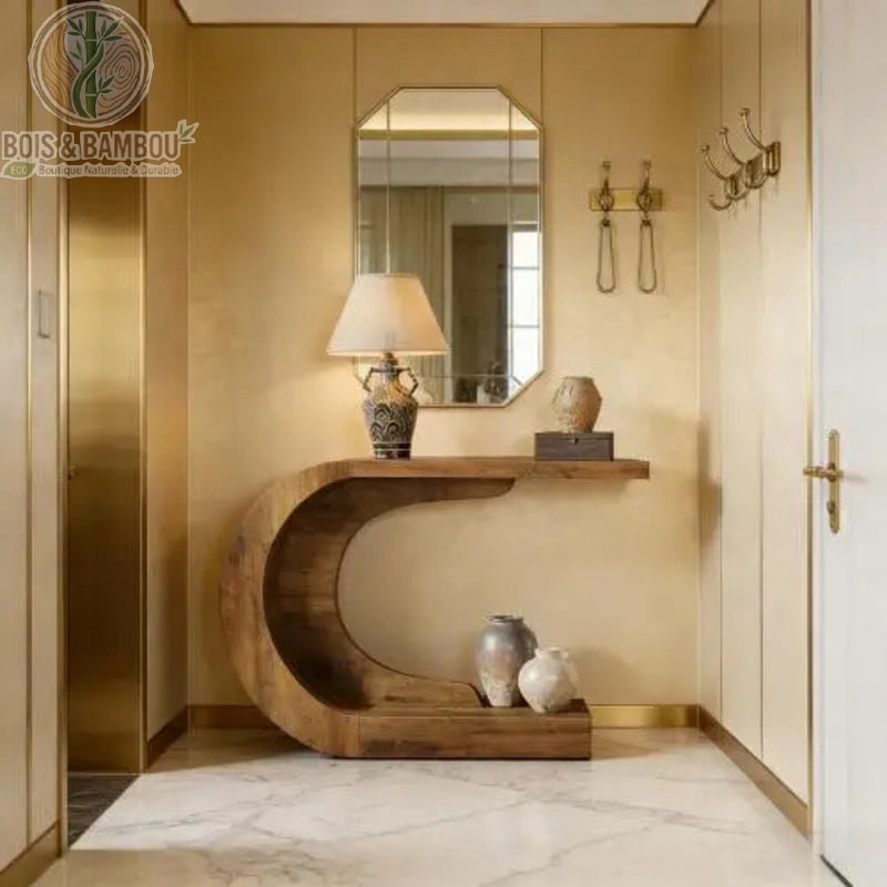 Console En Bois Massif Moderne En Forme De C situation 2. Console d'entrée design en bois massif aux courbes en C, sublimant un hall luxueux avec une lampe ancienne et des vases sous un miroir doré.