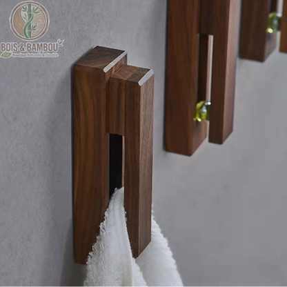 Crochet mural nordique en bois. Porte-serviette design en bois sombre fixé au mur, maintenant une serviette blanche par insertion. Style minimaliste et fonctionnel pour salle de bain.