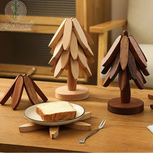 Dessous de Plat en Forme d'Arbre. Ensemble de dessous de plat pliables en bois formant des sapins décoratifs. Un modèle ouvert supporte une assiette sur une table en bois massif.