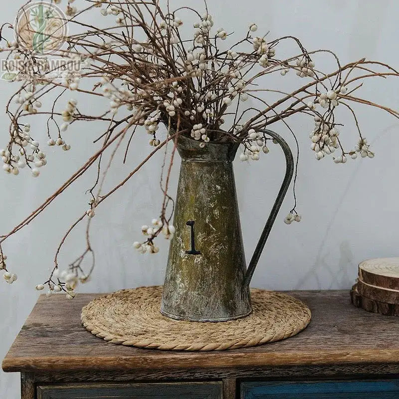 Dessous de Plat en Rotin Tressé utilisé comme napperon décoratif sur table en bois sombre avec vase et fleurs séchées
