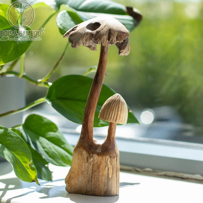 Sculpture champignon bois duo posée devant un feuillage vert