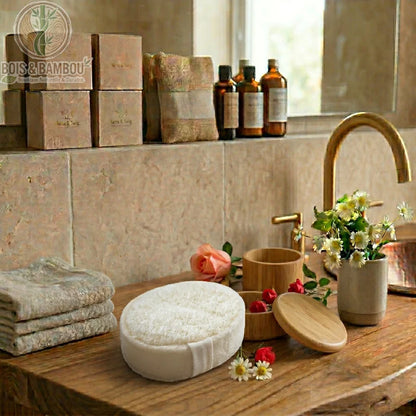 Éponge de Luffa Naturelle blanche de forme ovale sur un meuble en bois. Décor de salle de bain avec fleurs, serviettes, boîtes et pots en bois dans une ambiance zen et rustique.