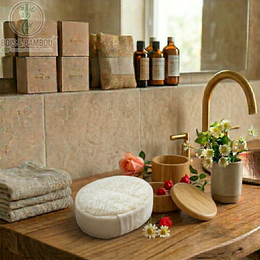 Éponge de Luffa Naturelle blanche de forme ovale sur un meuble en bois. Décor de salle de bain avec fleurs, serviettes, boîtes et pots en bois dans une ambiance zen et rustique.
