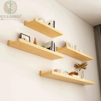 Etagere en bois massif flottante situation. Quatre étagères murales flottantes en bois clair disposées en quinconce, décorées de livres et objets d'art sur un mur blanc épuré.