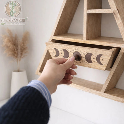 Main ouvrant le tiroir gravé phases de lune d'une étagère murale triangulaire en bois