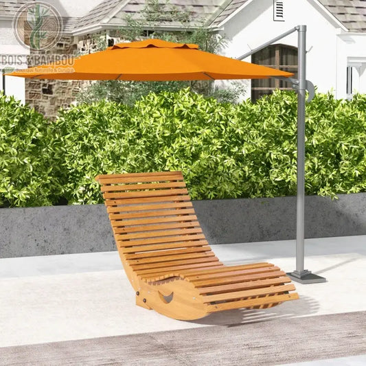 Fauteuil à Bascule Ergonomique. Un bain de soleil incurvé en lattes de bois clair placé sous un grand parasol orange déporté, devant une haie verdoyante et une maison blanche.