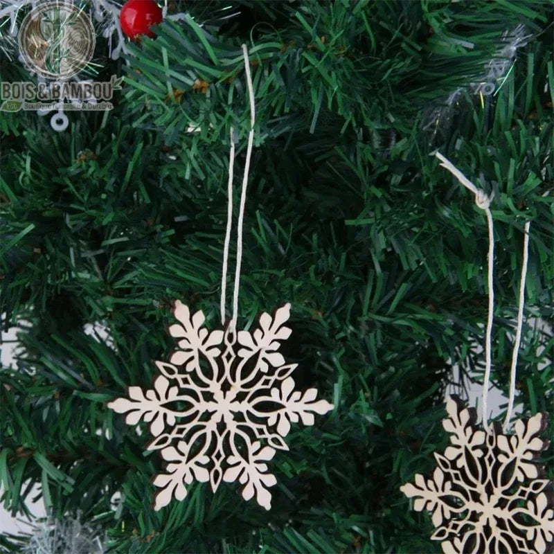 Flocons de neige en bois ajourés suspendus à un sapin de Noël artificiel vert avec baies rouges
