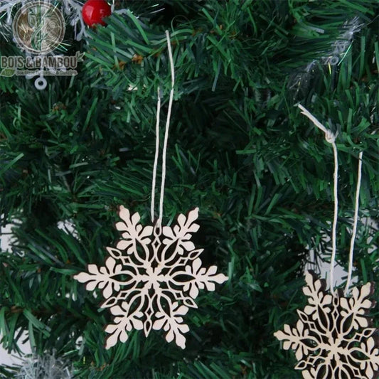 Flocons de neige en bois ajourés suspendus à un sapin de Noël artificiel vert avec baies rouges