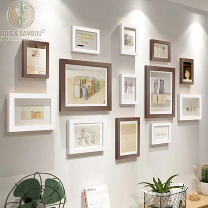Galerie Murale en Bois Massif Héritage, une composition de douze cadres photo alternant le bois sombre et le blanc pur, mettant en valeur des croquis et des citations inspirantes dans un agencement moderne sur un mur clair.