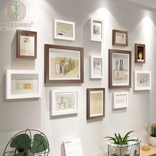 Galerie Murale en Bois Massif Héritage, une composition de douze cadres photo alternant le bois sombre et le blanc pur, mettant en valeur des croquis et des citations inspirantes dans un agencement moderne sur un mur clair.
